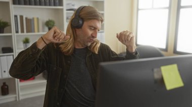 Monitörün yanındaki masada kulaklıkla dans eden sıradan sarışın bir adam, neşeli, üretken bir rutin..