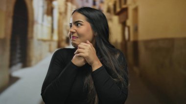 Gündüz vakti canlı eski kasaba sokaklarında gülümseyen bir kadın sıcak bir ortam ve kültürel zenginlik sergiliyor. Neşeli bir ifadeyle açık havada Latince bir özü yakalıyor..