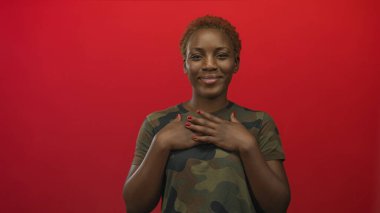 Kamuflaj üniformalı genç kadın stüdyoda göğüs göğüse çalışırken ileriye bakıyor..