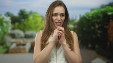 Taş bankın yanındaki ormanda yapraklı tepe örtüsü altında eklemlerini ısıran bir kadın..