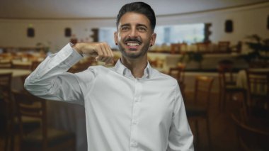 Genç İspanyol adam, restoranın yemek odasında bulanık sandalye ve masalara karşı pazılarını esnetiyor..