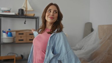 Yeni daireden hoşlanan bir kadın yeni bir başlangıç ve neşeyi simgeleyen raflarla dolu parlak oturma odasındaki kutularla çevrili.