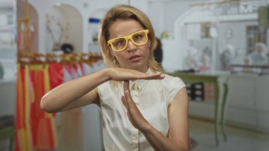 Sarı gözlüklü genç sarışın bir kadın perakende binasında mola veriyor..