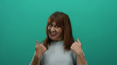 Uzun saçlı İspanyol son sınıf öğrencisi, yeşil bir arka plana karşı hoş geldin jestleri yapıyor. Sıcak ve arkadaşça bir ifade takınıyor..