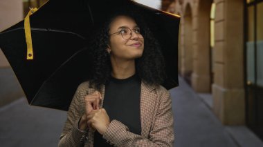 Şemsiyenin altında gülümseyen bir kadın huzurlu bir günde neşeli ve sıcak bir hava yayıyor. Çevresindeki canlı doğa deneyimini çevreleyen klasik bir mimarisi var..