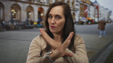 Sokakta kollarını kavuşturmuş bir kadın şehir ortamında reddediyor..