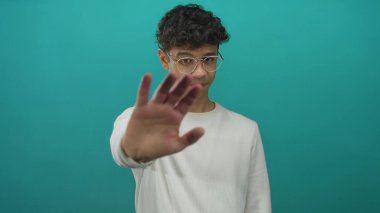 Beyaz süveterli ve yuvarlak gözlüklü bir adam avucunu ileri uzatır..