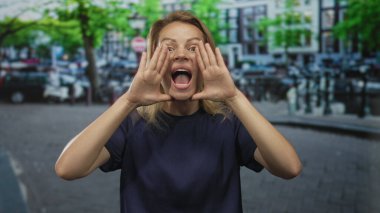 Kalabalık bir caddede elleri ağzında bağıran genç sarışın kadın, heyecan..