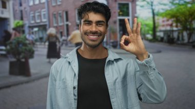 Erkek el ele tutuşur Tamam işareti sokakta gülümserken bulanık yayaların ortasında; onay güven mutluluğu.