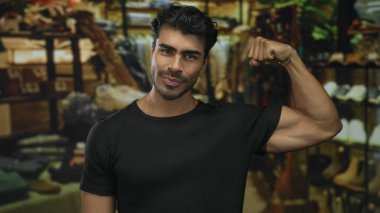 Adam, binanın içindeki bir giyim mağazasında siyah bir gömlek giyerken pazılarını esnetiyor; kendine güven.