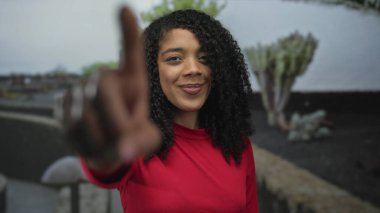 Yeşil parktaki kırmızı tepede gülümseyen kadın bulutlu gökyüzünün altında, çöl sularının ortasında, taş yol boyunca. Mutluluk..