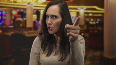 Canlı kumar makineleriyle dolu bir kumarhanede oturan ve işaret eden kadın heyecan ve beklentiyi yansıtıyor..