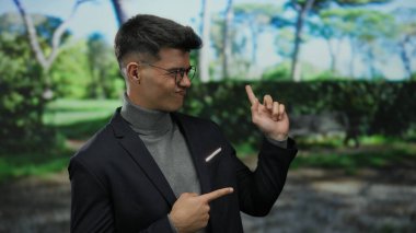 Açık hava parkında gülümseyen İspanyol bir adam gözlüklü ve günlük ceketli, kendine güvenen ve doğal çevrede çekici bir tavır sergiliyor.