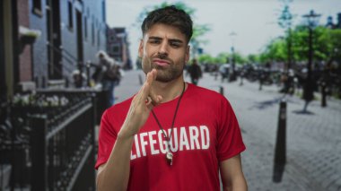 Gündüz vakti güneşli bir şehir sokağında kırmızı gömlekli genç İspanyol cankurtaran el ele tutuşuyor..