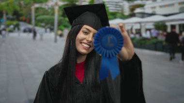 Mezuniyet üniformalı İspanyol kadın, şehir sokaklarında mavi kurdeleyle gururla geziyor. Şehir ortamının başarısını ve başarısını simgeliyor..