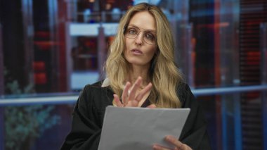 Üniformalı bir kadın otelin içinde dokümanları okurken, odaklanmış bir ifadeyle, otoriteyi ve konsantrasyonu aktarıyor..