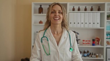 Klinikte steteskoplu dans eden kadın hastane odasında üniformalı genç sarışın bir doktor..