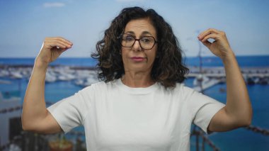 Limanda el kol hareketi yapan orta yaşlı İspanyol kadın; iletişim ifadesi hikaye anlatma bağlantısı.