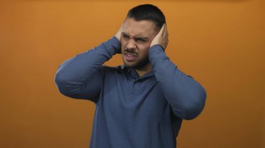 Surat asarken canlı turuncu stüdyo duvarına karşı el ele tutuşan İspanyol genç adam. Aşırı stres..