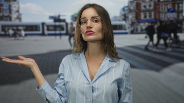 Genç İspanyol kadın, gözlüklü ve pembe rujlu çizgili mavi gömlekli yoğun şehir caddesinde el ele tutuşuyor..