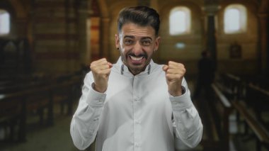 Kaldırılmış elleri, sıkılmış yumrukları ve kilisenin içinde ağzı açık, kemerli pencerelerin altındaki ahşap sıraların arasında duran adam; sürpriz.