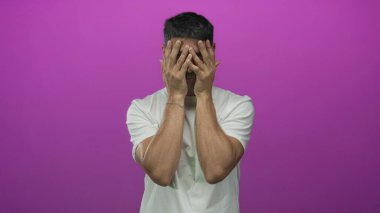 Stüdyoda beyaz t-shirt 'lü bir erkek yüzünü mora boyayarak kapatır. Utanç..