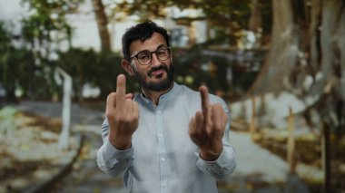 Parkta sakallı İspanyol bir adam yeşil ağaçların arasında meydan okuyarak doğal ortamda cesur bir ifade yaratabilir..