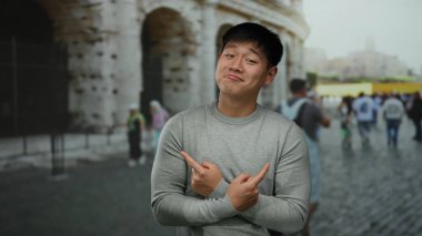 Arka planda bulanık bir sokak sahnesiyle tarihi Roma Stadyumu 'nun dışında güvenle poz veren genç Çinli bir adam..