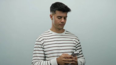 Beyaz arka planda telefon duruşu olan genç adam çizgili gömlek giyen ekrana odaklanmış.