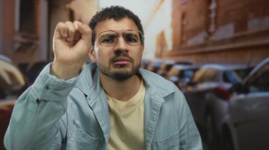 Kalabalık bir caddede dikkatle dinlerken gözlük takan İspanyol genç adam el ele tutuşuyor..