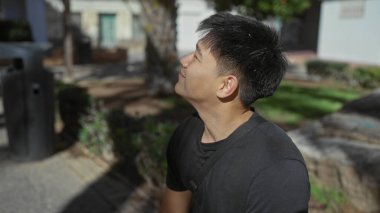 Güneşli bir günde gülümseyen genç bir adam, şehir ortamında pozitif bir şehir atmosferini yansıtırken yakalandı..