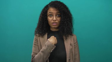 Gözlüklü ve ekose ceketli genç İspanyol kadın yeşil stüdyoda parmak göğse, inkar.