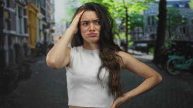 Beyaz atletli bir kadın, şehir caddesinde gündüz vakti kafası karışık binalarla el ele hareket ediyor..