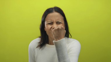 Beyaz kazaklı genç İspanyol kadın, öfke ve yoğunluğu betimleyen parlak sarı bir arka plana karşı güçlü duygular sergiliyor..