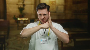 Sert ifadeli bir doktor, loş bir kilise ortamında boynuna steteskop takarak kavga eder..