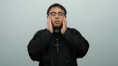 Papaz kıyafeti giymiş Asyalı bir adam arka planda sıkıntı içinde, duygularını ve dini temasını aktarıyor..