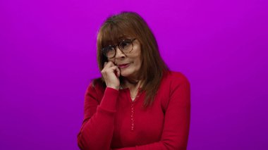 Gözlüklü, kırmızı süveter giyen, yüzünde pembe izole bir arka plan olan İspanyol bir kadın..