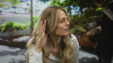 Odaklanmış bir portredeki bir sarışın olarak merakla dinlerken kadın elini cama vuruyor..