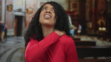 Tarihi bir kilise binasında boynunu sıkan kırmızı bluz giyen Afrikalı Amerikalı bir kadın..