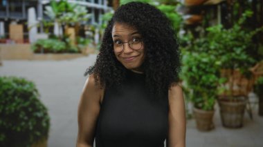 Gözlüklü genç İspanyol kadın bir sokakta sessizlik için parmaklarını dudaklarına uzatıyor..