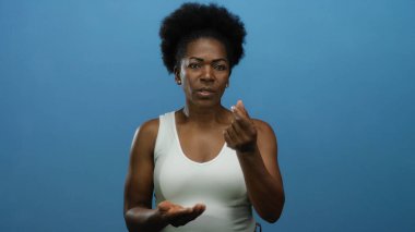 Kadın, mavi arka planda para işareti yapıyor. Finans ya da maaş kavramını anlamlı el hareketleriyle gösteriyor..