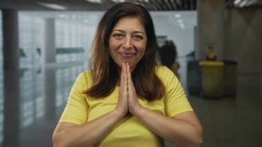 İspanyol kadın yoğun bir havaalanı terminalinde el ele tutuşup dua ediyor. Minnettarlık..