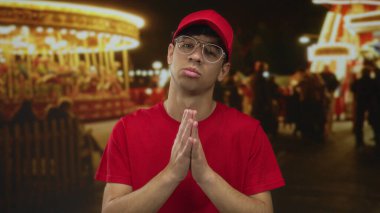 Geceleri parlayan karnaval ışıklarının arasında kırmızı şapkalı ve kırmızı gömlekli bir adam, vicdan azabı..