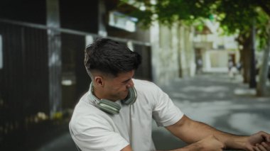 Kulaklıklı genç İspanyol bir adam şehir caddesinde hareket ediyor, dışarıda çabalıyor..