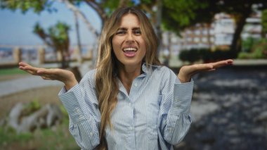 Genç sarışın kadın, sahil kenarında palmiyelerini palmiye ağaçları ve beton bariyerlerin altında silkeliyor..