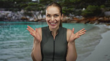 Kadın, turkuaz suyun yanındaki sakin kumlu sahil şeridinde çıplak ellerini çırpıyor..