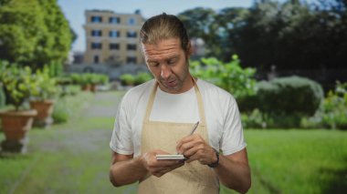Sarı önlüklü, uzun saçlı, elinde not defteri ve kalemle yeşil bitkilerin arasına sipariş yazıyor..