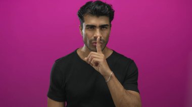 Mor stüdyoda sessizlik için parmaklar dudaklara genç İspanyol adam; gizlilik dinginlik gizemi.