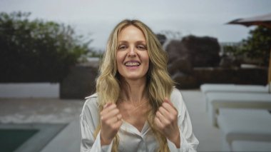 Havuz manzaralı bir kadın, genç sarışın tatil köyü manzaralı açık hava manzaralı ve ışıl ışıl bir gülümsemeyle tamamlanmış..