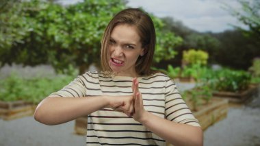 Yeşil park yolunda kaşlarını çatarken yumruğunu sıkan ve boş bir yeri işaret eden kadın; öfke..